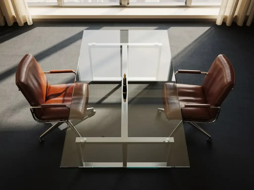 Two mahogany conference chairs at glass table with fountain pen in centre, natural light through windows in modern boardroom